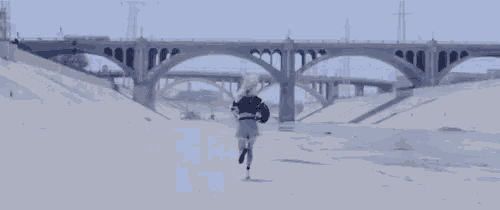 a woman is running in front of a bridge on a sandy beach .