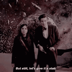 a man and a woman are standing next to each other in front of an explosion . the man is holding a gun .