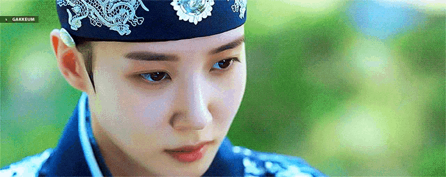 a close up of a woman wearing a blue hat and a traditional korean dress .