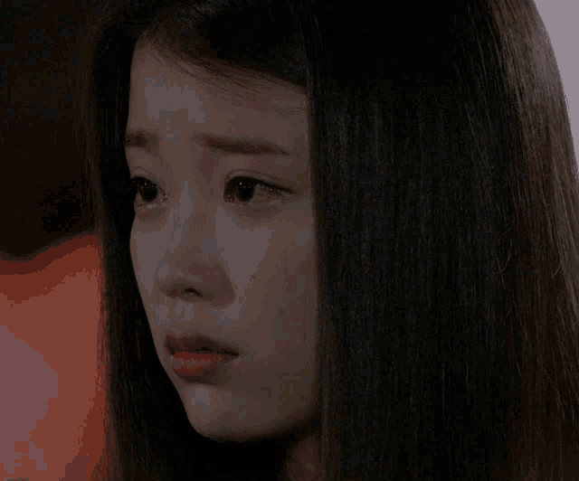 a woman with long hair is crying with a tear coming out of her eye