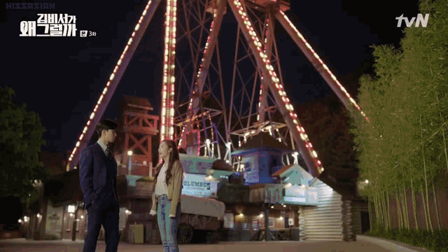 a man and a woman are standing in front of a ferris wheel that says tvn