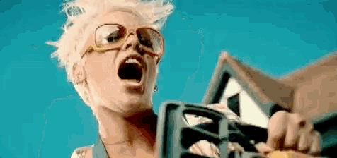 a woman wearing glasses and sunglasses is holding a chainsaw in her hand .