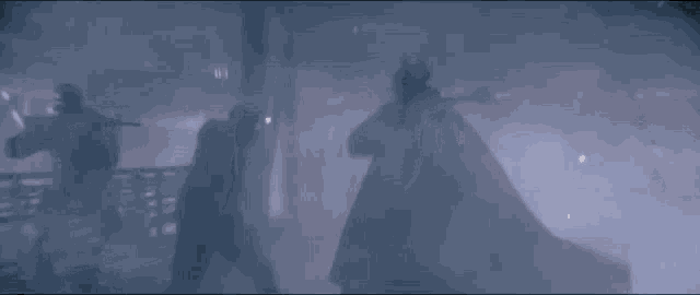 a man in a cape is standing in a dark room in the rain .