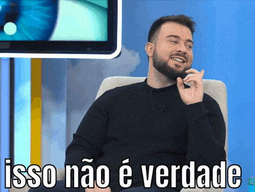 a man with a beard is sitting in front of a television with the words isso não e verdade written on the bottom