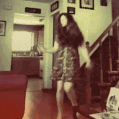 a woman in a dress is dancing in a living room .
