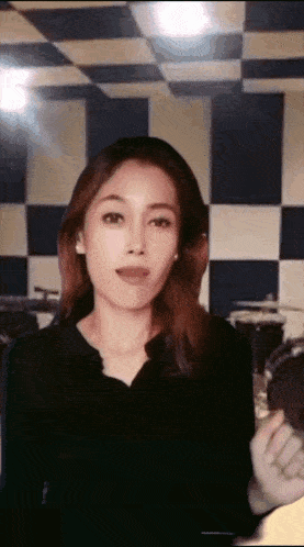 a woman stands in front of a checkered wall