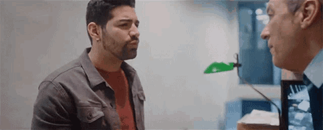 two men are talking to each other in a room .