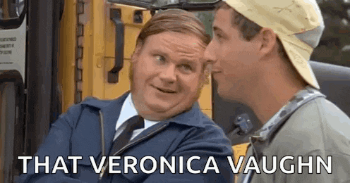 a man in a suit and tie is talking to another man in front of a yellow bus .
