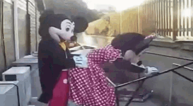 mickey mouse and minnie mouse are standing next to each other and having sex .