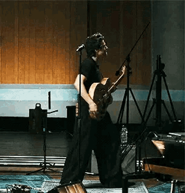 a man is playing a guitar in front of a microphone in a recording studio .