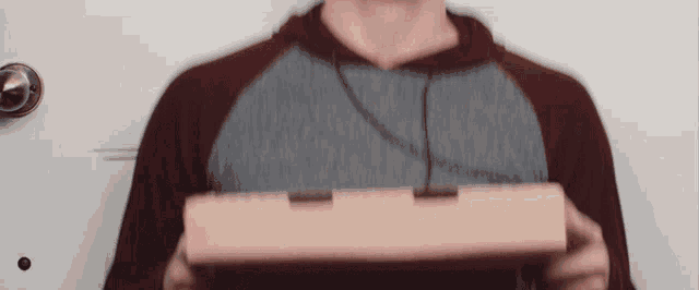 a man in a hoodie is holding a box in his hands