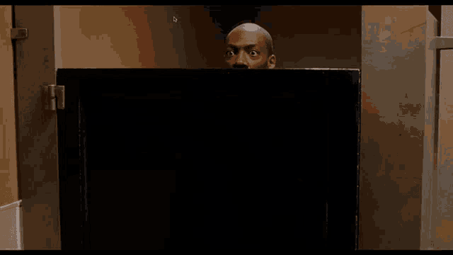 a man is peeking out from behind a black barrier