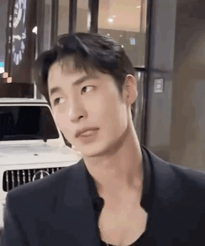 a man in a suit is standing in front of a white mercedes benz .