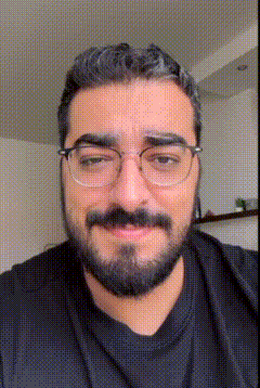 a man with a beard wearing glasses and a black shirt .
