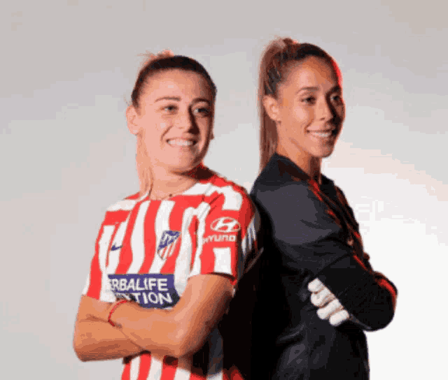 a woman in a herbalife shirt stands next to a woman in a hyundai jersey