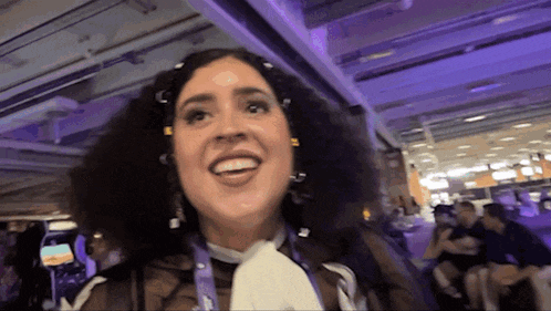 a woman with curly hair is smiling and wearing a lanyard around her neck