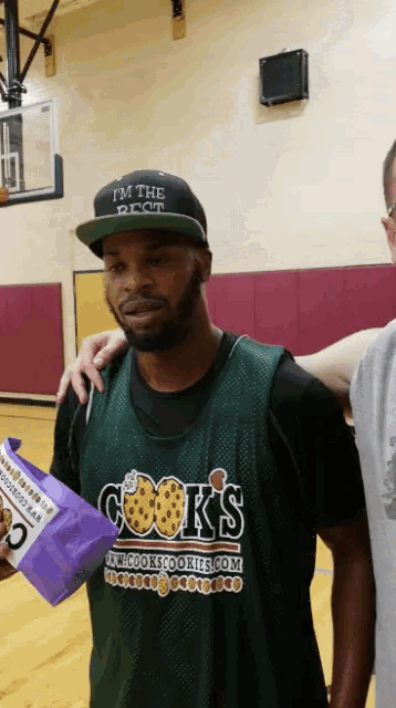 a man wearing a hat that says i 'm the best is standing on a basketball court