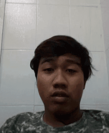 a young man with short hair is making a funny face in front of a white tiled wall .