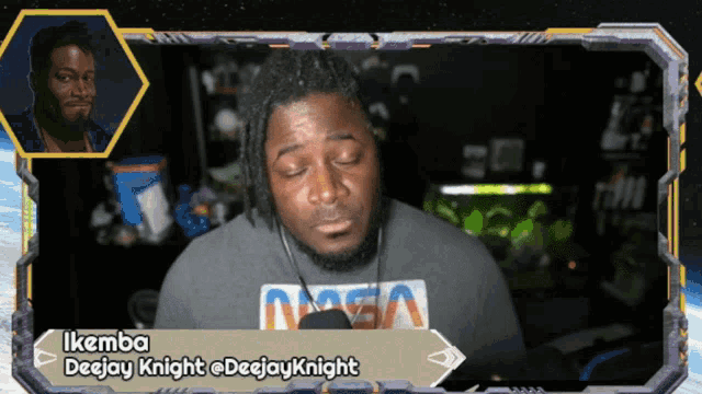 a man wearing a nasa shirt talks into a microphone with the name ikemba on the bottom