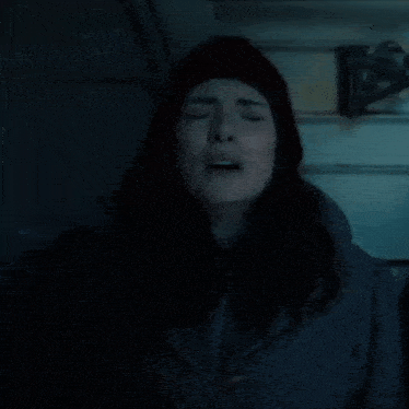 a woman with her eyes closed wearing a beanie