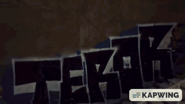 a person is standing in front of a wall that has graffiti on it that says sniper