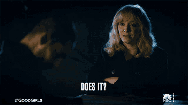 a woman sitting at a table says " does it " while talking to a man
