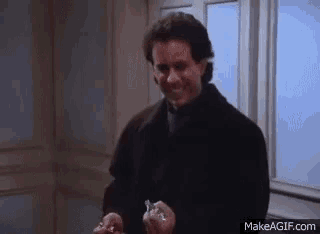 a man in a black coat is holding two keys in his hands in front of a door .