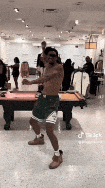 a man is dancing in front of a pool table in a store .
