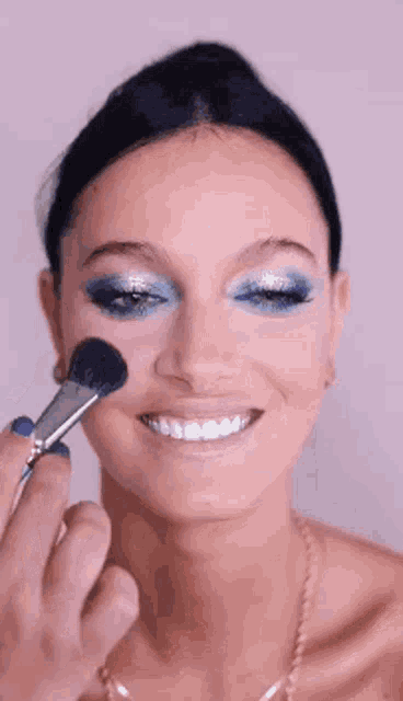 a woman is smiling while getting her makeup done .