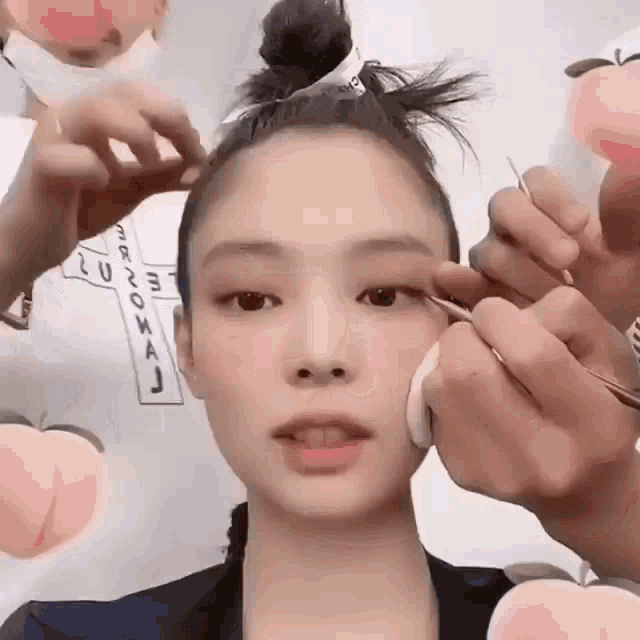 a person is applying makeup to a woman 's face with a peach in the background .