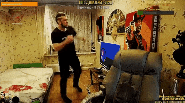 a man dancing in a room with a red dead redemption poster behind him