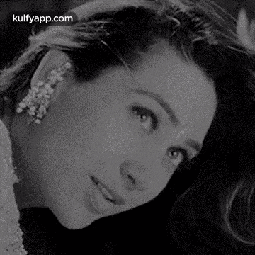 a black and white photo of a woman with long hair and earrings .