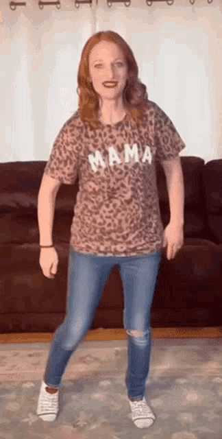 a woman wearing a leopard print mama t-shirt is dancing in a living room
