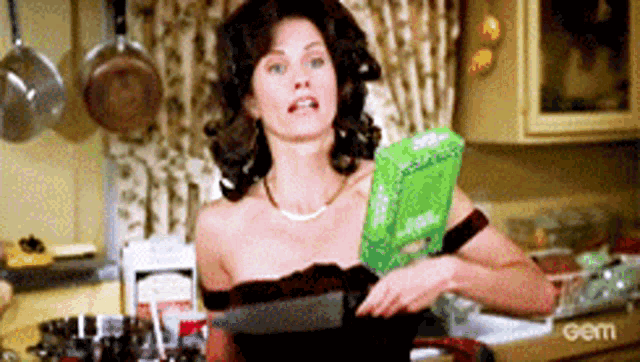 a woman in a black dress is holding a bag of food in a kitchen ..