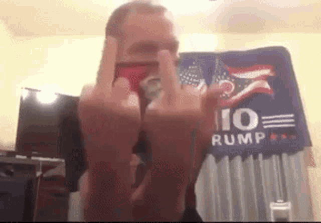 a man is giving the middle finger in front of a rump banner .