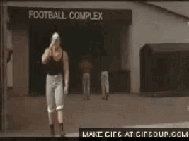 a man in a mask is running in front of a football complex .