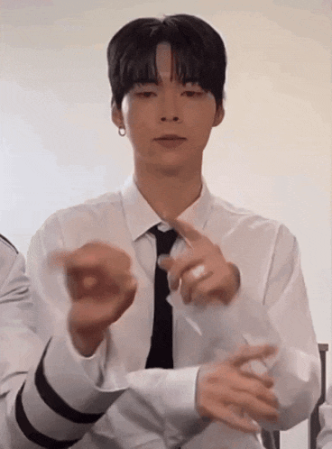 a man in a white shirt and black tie is making a gesture with his hands .