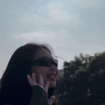 a woman wearing sunglasses is smiling and waving at the camera