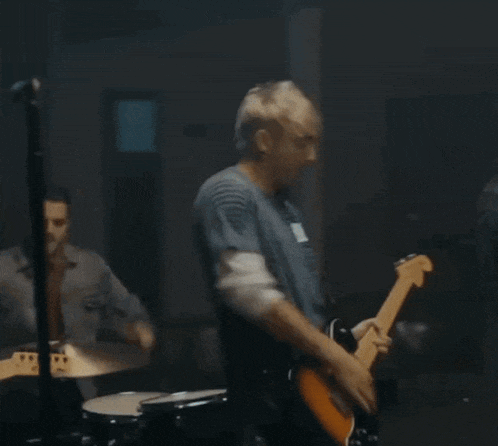 a man singing into a microphone while another man plays guitar