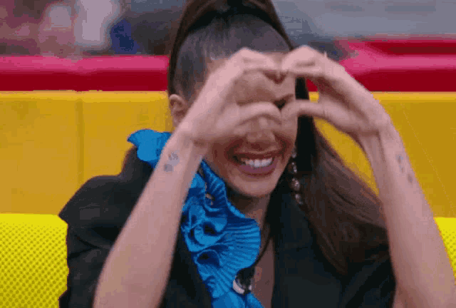a woman making a heart with her hands over her eyes