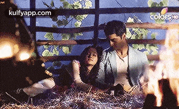 a man and a woman are laying on a pile of hay .