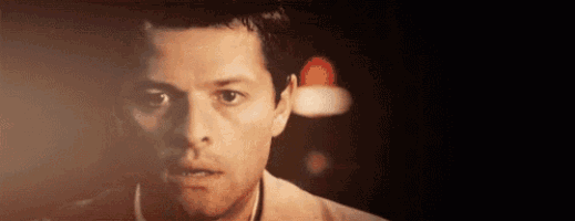 a close up of a man 's face in a dark room with a lamp in the background .