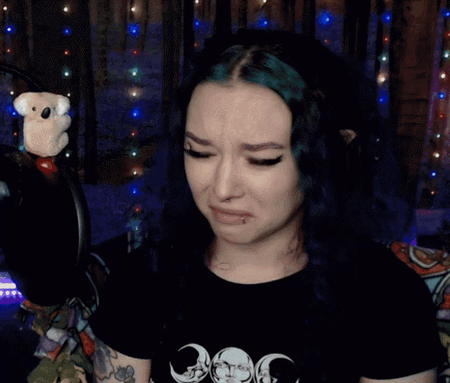 a woman with green hair is wearing a black shirt with a crescent moon on the front