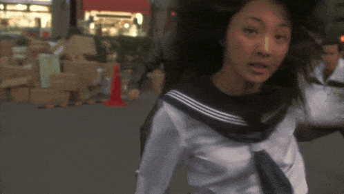 a girl in a school uniform is walking down a street