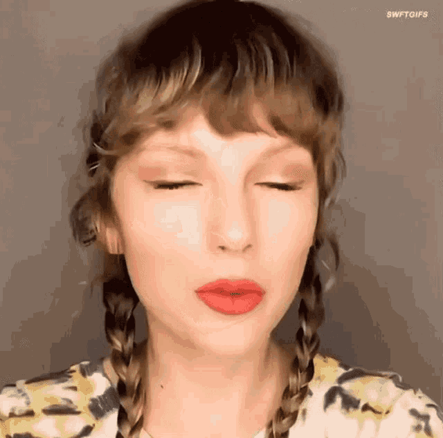 taylor swift is wearing red lipstick and braids .