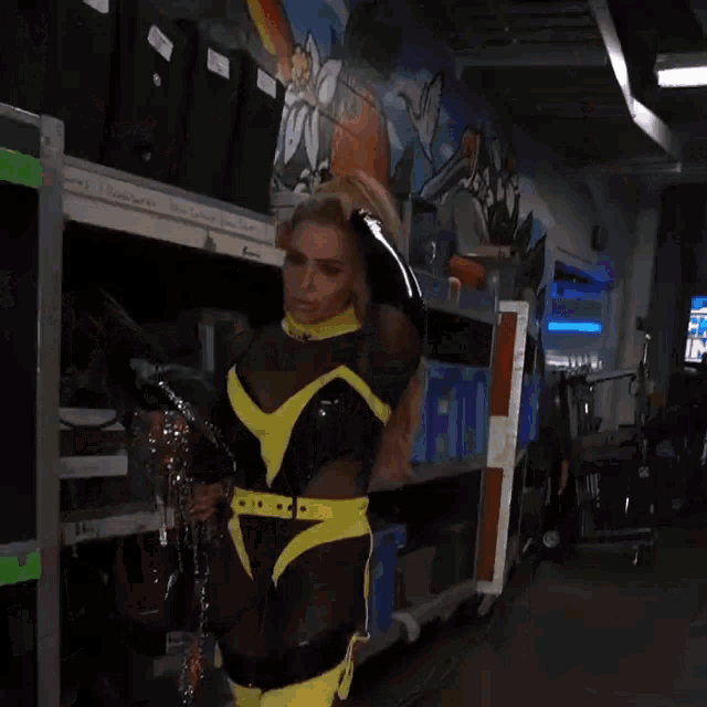 a woman in a black and yellow outfit holds chains in her hand