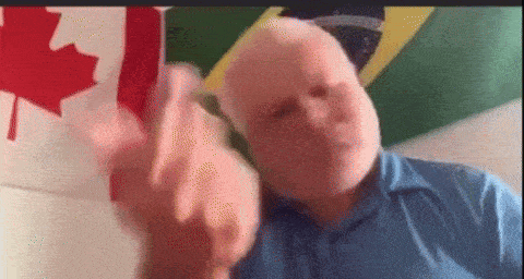 a man in a blue shirt is making a funny face in front of a canadian flag and a brazilian flag .