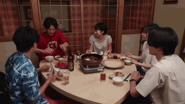 a group of people are sitting around a table with plates of food and drinks