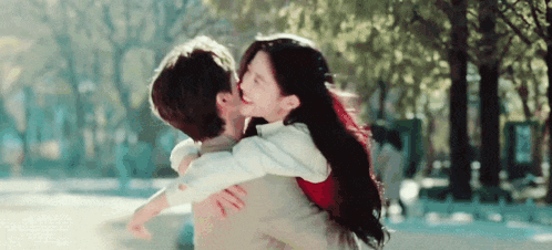 a man is carrying a woman in his arms and kissing her .
