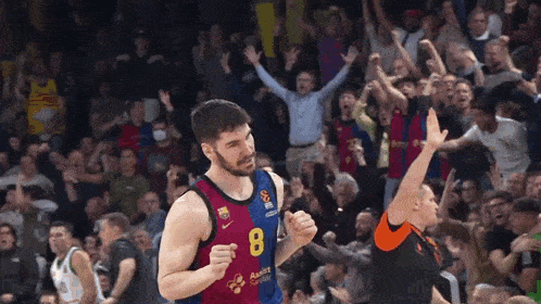 a basketball player wearing a number 8 jersey stands in front of a crowd